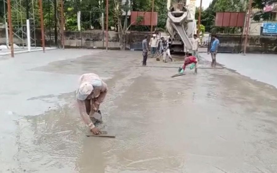 Workers screeding a wet concrete sub-base on a ground under construction