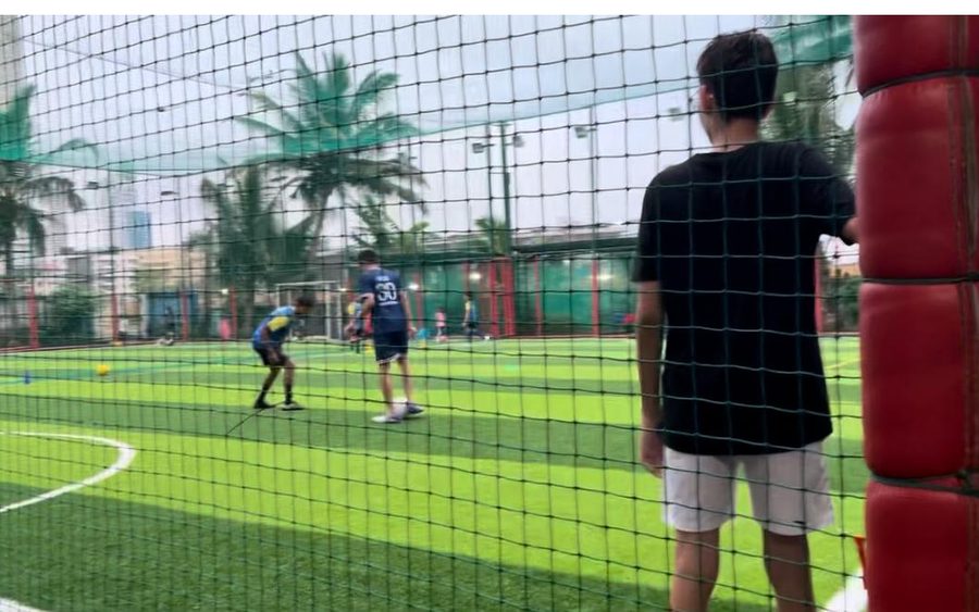 Football being played inside a netted enclosure with padded red posts