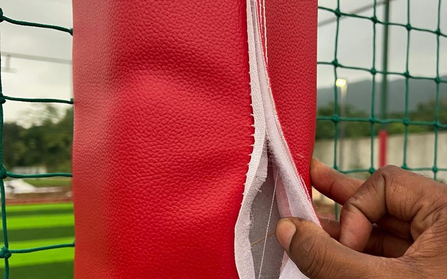 Red rexine padding being wrapped around a steel post