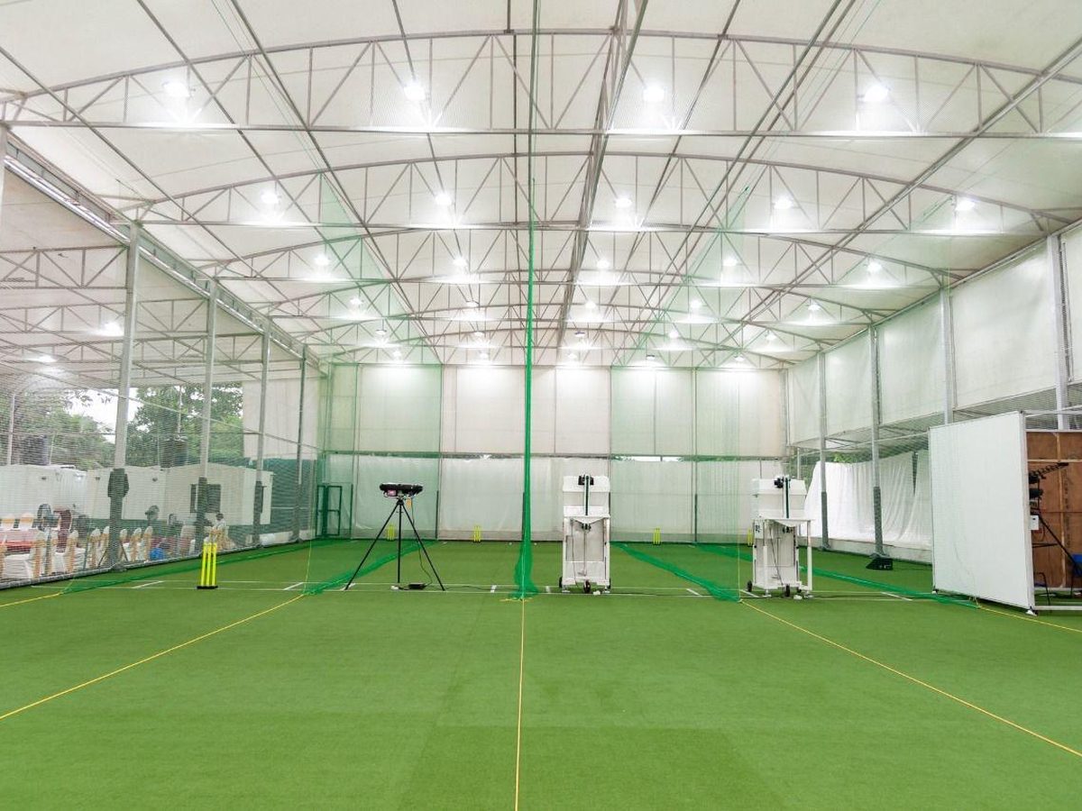 Indoor cricket facility with green turf, lane netting and a tensile sheet roof